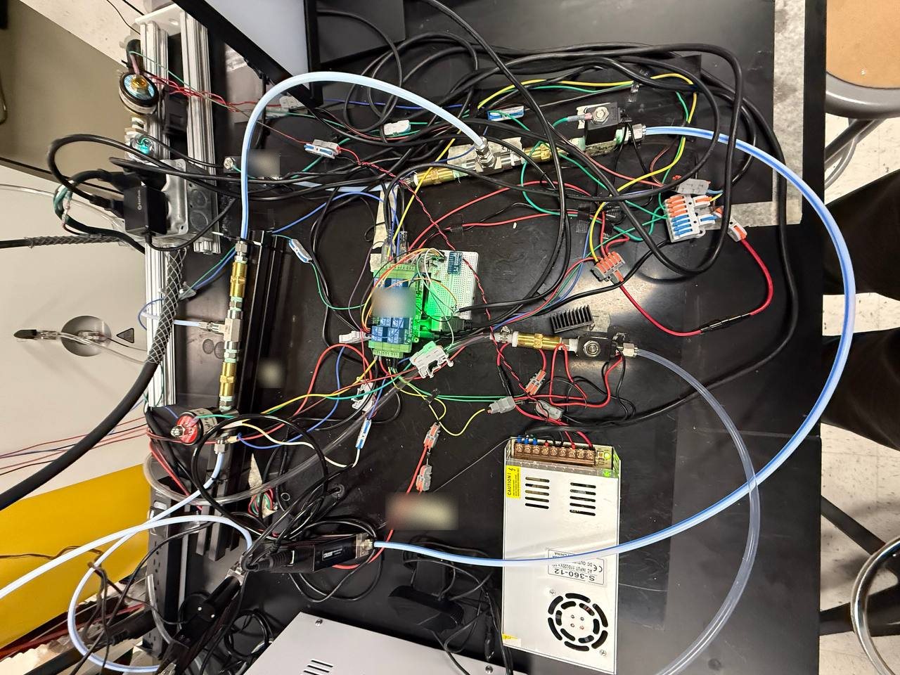 Top-down view of the furnace controller bench with a Raspberry Pi relay board, brass fittings, solenoid valves and a 12 V power supply