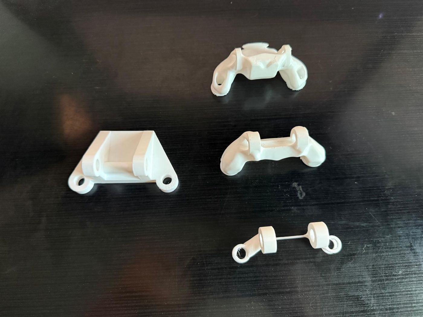 Four 3D-printed bracket designs on a desk